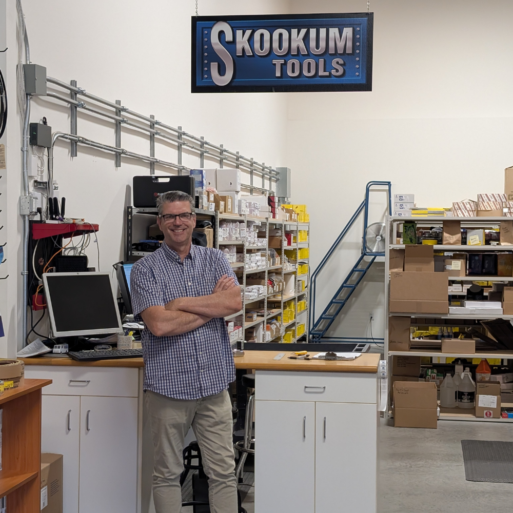 Robert McDonald in the Skookum Tools warehouse beneath the Skookum sign