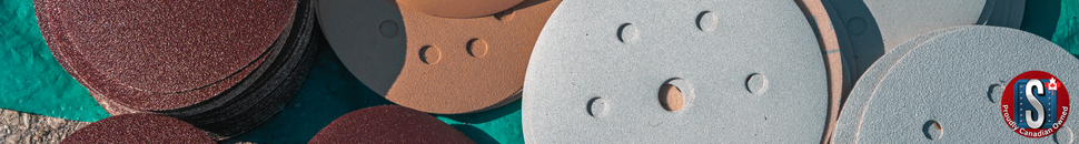 A close-up view of stacked sanding discs in various grits and colors, including maroon, tan, and grey. The image highlights their abrasive texture and circular shapes, with the Skookum Tools “Proudly Canadian Owned” logo in the bottom right corner